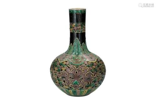 A sancai porcelain vase with relief decor of leaves and devi...