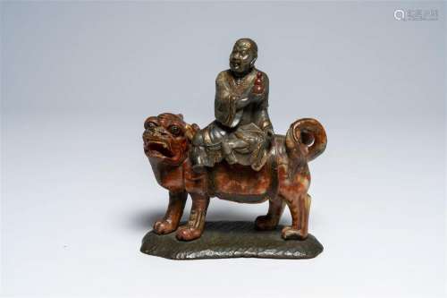 A Chinese soapstone 'arhat on lion' sculpture with wooden st...