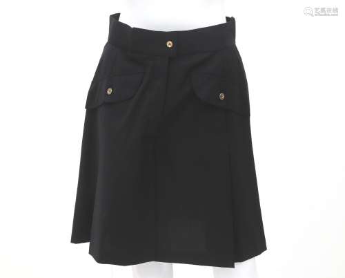 A black Chanel a-line pleated skirt. The skirt has two pocke...