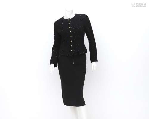 A Chanel Boutique ensemble of a black blazer and a skirt. Th...
