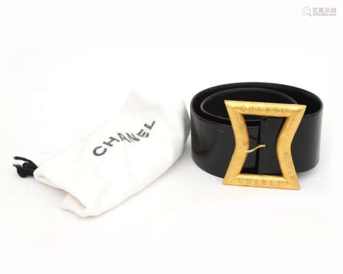 A black patent leather Chanel belt with gilded buckle. Incl....