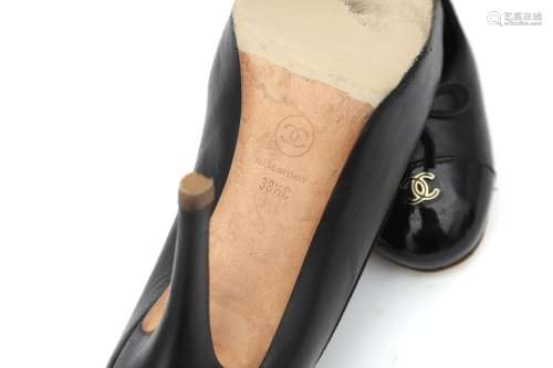 A pair of Chanel black leather and patent pumps. A round pat...