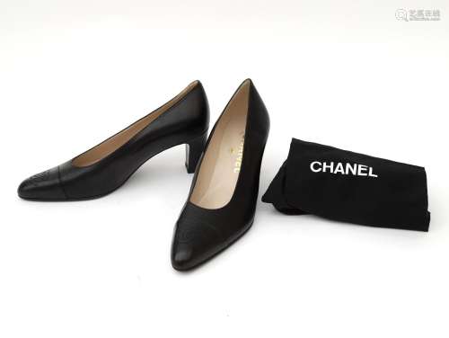 A pair of unworn black leather Chanel pumps. With embroidere...