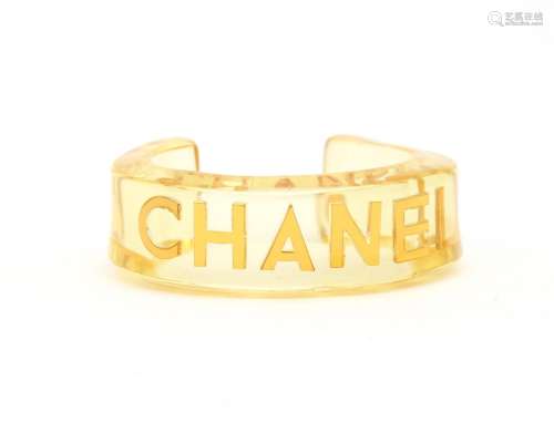 A perspex Chanel bangle. A rigid open bangle with gold lette...