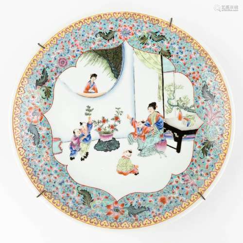 A Chinese porcelain plate, decorated with a lady and playing...