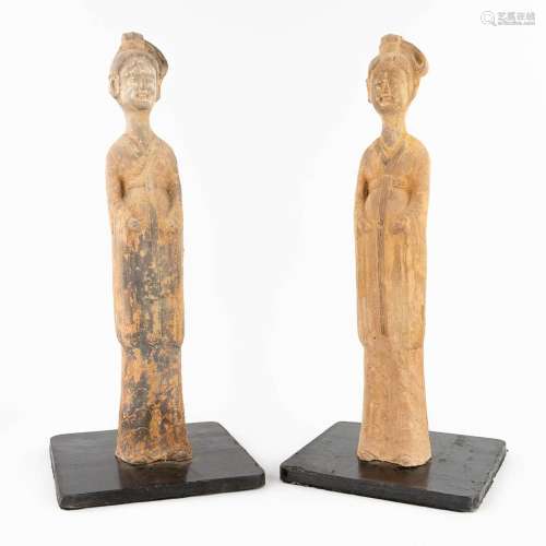 A pair of Chinese standing figurines, standing on a wood bas...