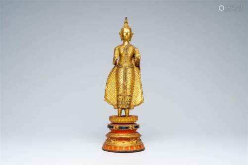 A Thai gilt bronze figure of a standing Buddha on a polychro...