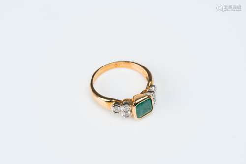 An 18 carat white and yellow gold ring set with an emerald a...