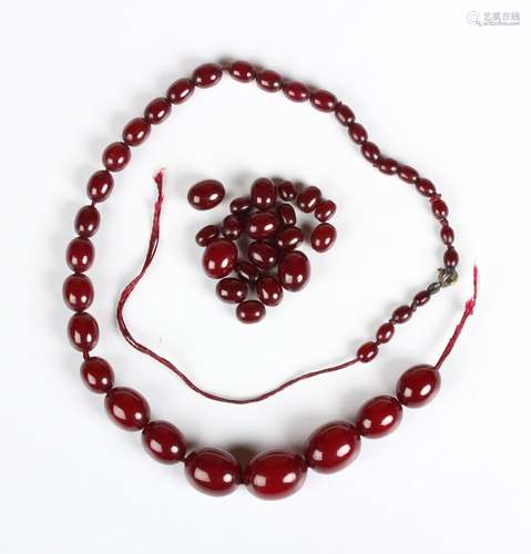 A single row necklace of graduated oval cherry coloured imit...