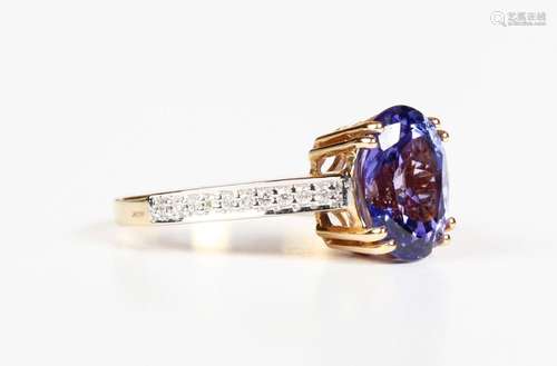 An 18ct gold ring, claw set with an oval cut tanzanite betwe...