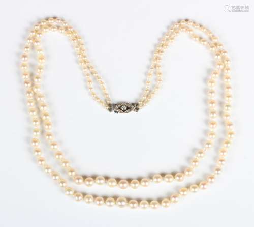 A two row necklace of graduated cultured pearls on a diamond...