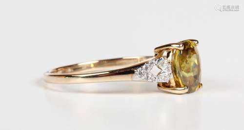 A 9ct gold ring, claw set with an oval cut sphene between co...