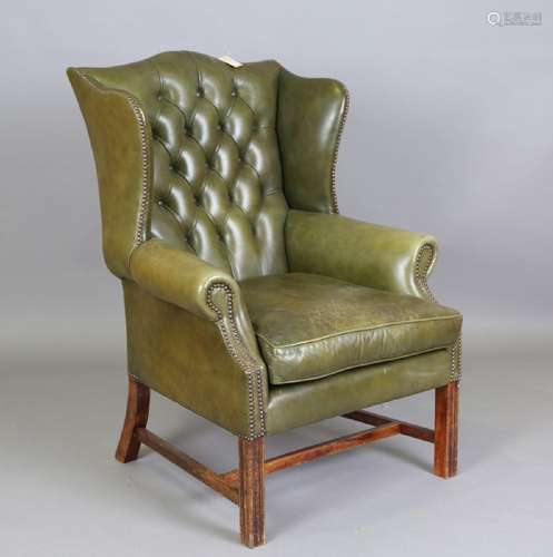 A 20th century George III style wing back armchair, upholste...