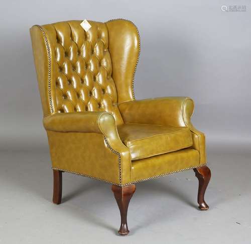 A 20th century wing back armchair, upholstered in buttoned l...