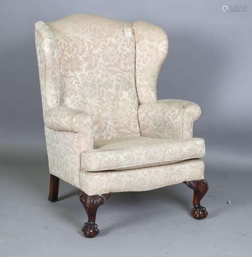 A 20th century George III style wing back armchair, raised o...