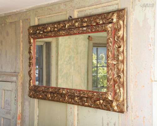 AN ITALIAN CARVED GILTWOOD AND RED PAINTED MIRROR, POSSIBLY ...