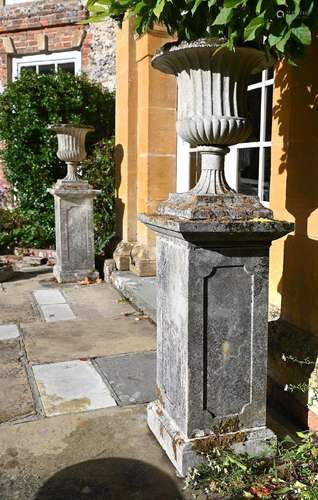 A PAIR OF COMPOSITION STONE CAMPANA URNS ON PLINTHS, LATE 19...