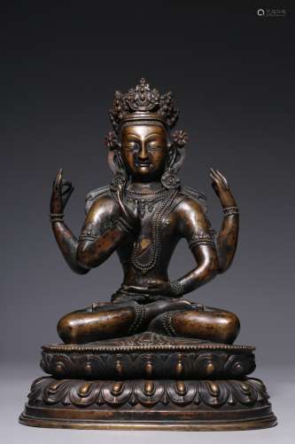 A bronze seated statue of Guanyin with four arms from the Qi...