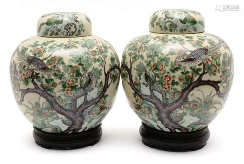 A pair of large lidded famille verte jars on wooden stands