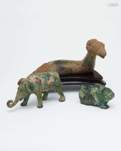 Three bronze figures of a reclining ram, an elephant and a r...