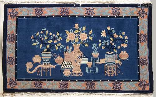 A BLUE GROUND CARPET WITH OBJECTS AND FLOWERS
