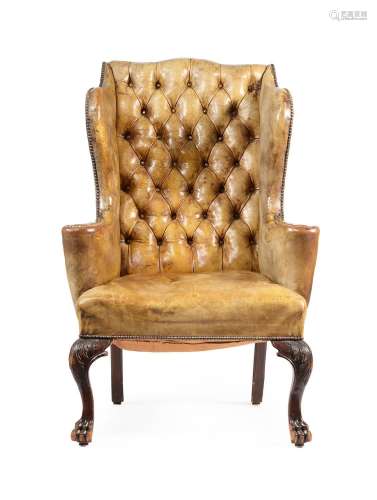 A WALNUT WING ARMCHAIR UPHOLSTERED IN GREEN LEATHER, IN GEOR...