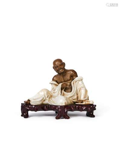 A LARGE CHINESE SHIWAN FIGURE OF A SEATED LUOHAN ON A ROSE W...