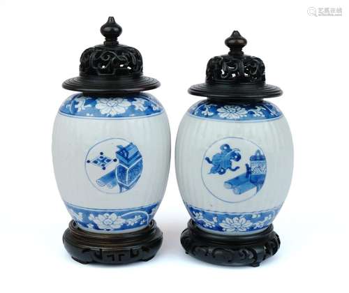 A pair of blue and white tea canisters with wooden lids