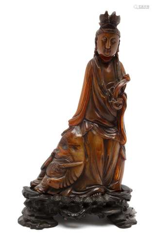 A carved buffalo horn Guanyin on wooden stand