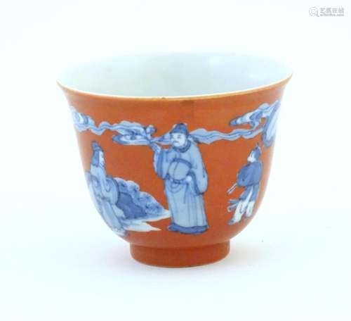 A Chinese tea bowl with a red ground decorated in blue with ...