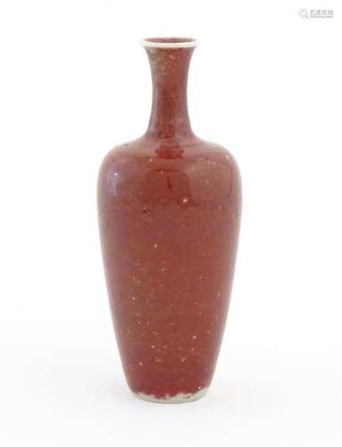 A Chinese vase of tapering baluster form with a red glaze. C...