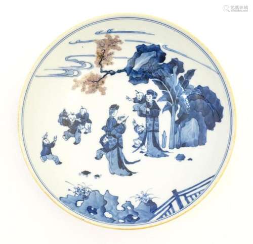 A Chinese blue and white dish decorated with figures in a ga...