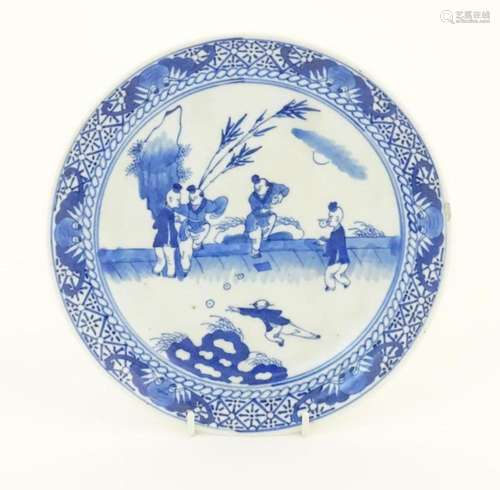 A Chinese blue and white plate decorated with figures in a g...