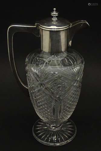 A cut glass claret jug with silver plate mounts and handle. ...