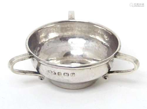 A small silver three handled bowl with hammered decoration, ...