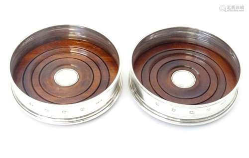 A pair of silver bottle coasters with turned wooden bases, h...