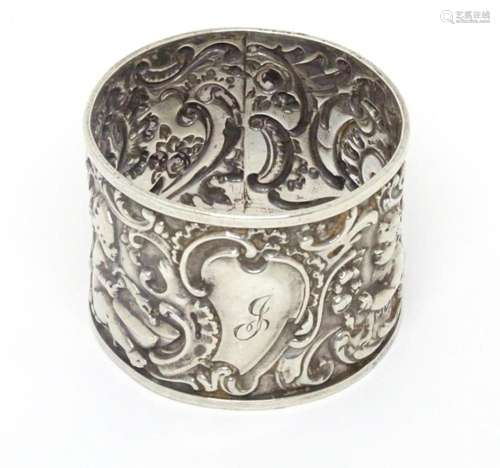 A Victorian silver napkin ring with embossed putti decoratio...