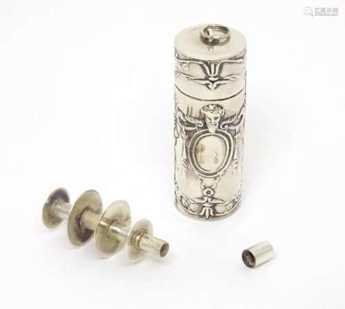 A silver sewing thread spool / needle case with embossed dec...