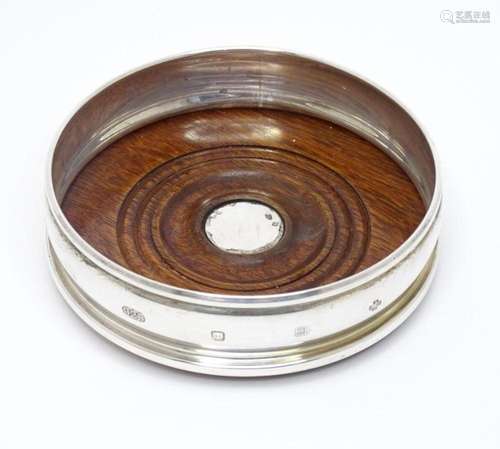 A silver bottle coaster with a turned wooden base, hallmarke...