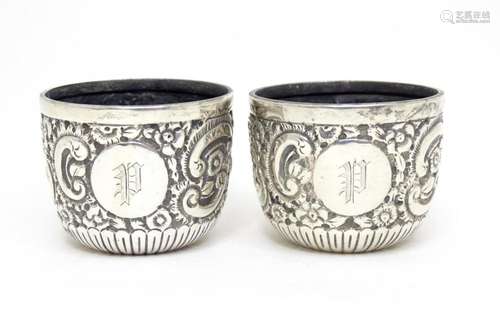 A pair of Victorian silver salts with embossed decoration ha...