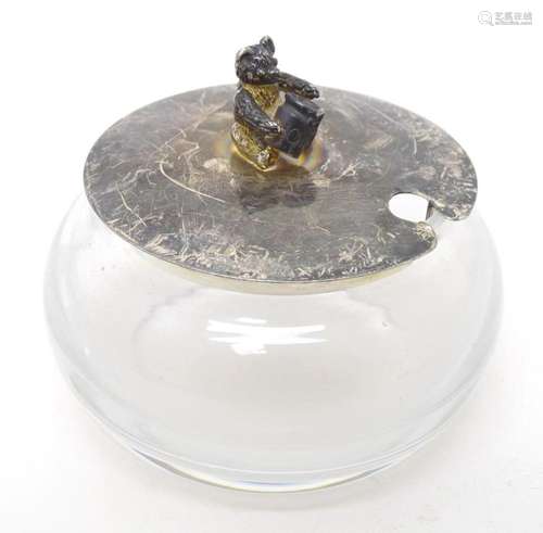 A glass honey pot with silver lid the handle formed as a sea...