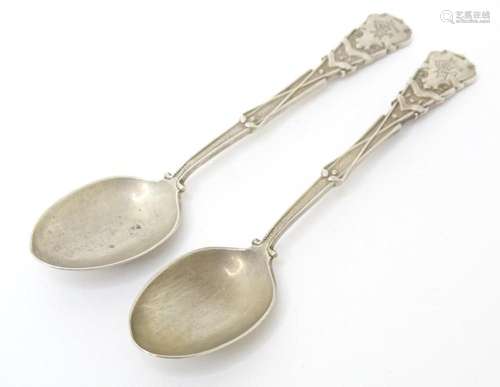 A pair of silver spoons decorated with golf clubs, golf ball...