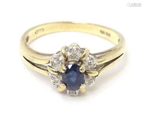 A 9ct gold ring set with central sapphire bordered by diamon...