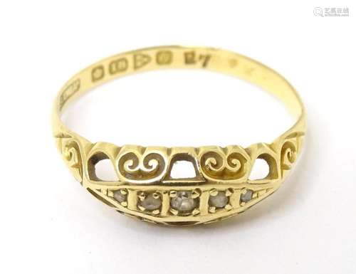 An 18ct gold ring set with 5 diamonds and having scroll deta...