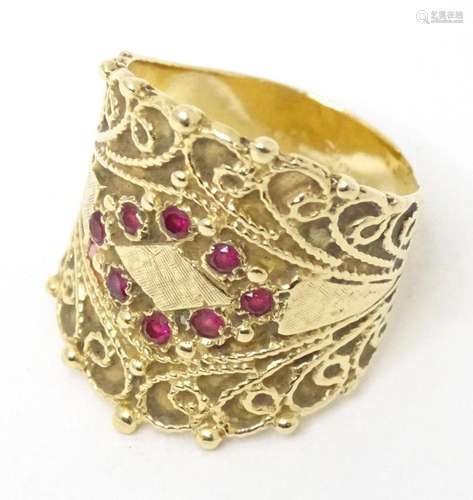 A gold ring with scroll detail and set with 8 rubies. Ring s...