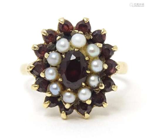 A 9ct gold ring set with garnets and seed pearls. Ring size ...