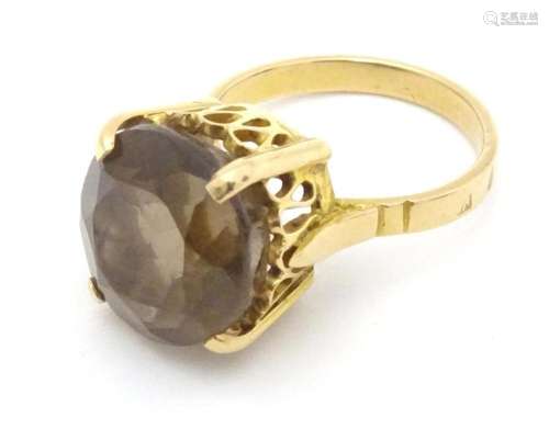 A yellow metal ring set with with central smoky quartz. Ring...