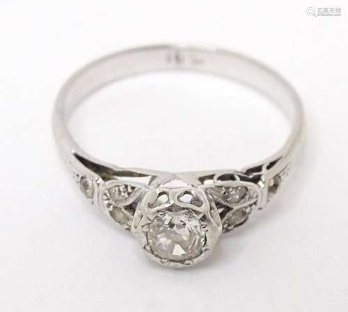 An 18ct white gold ring set with central diamond flanked by ...