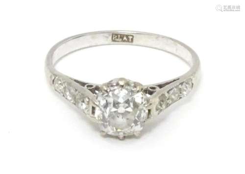 A platinum ring set with central diamond flanked by three di...