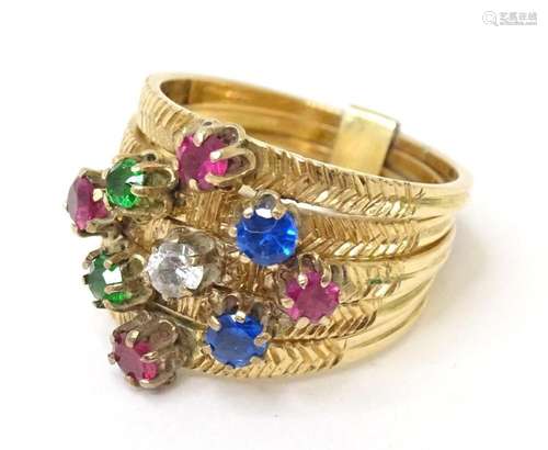 A yellow metal ring set with coloured stones. Ring size appr...